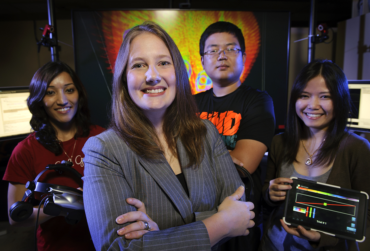A picture of four people smiling at the camera in a technology lab.